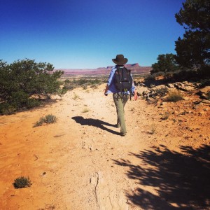 woman hikes in the desert surrounded by juniper trees